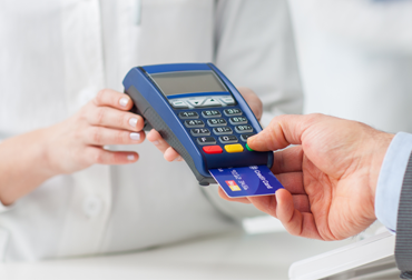 Ein Kunden zahlt bargeldlos mit einer Kreditkarte. Dazu nutzt er das Kartenlesegerät.